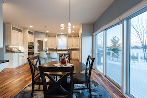 Open transition from dining to kitchen with inviting wide plank ash wood flooring throughout